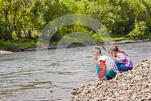 Children boy and girl playing near the river