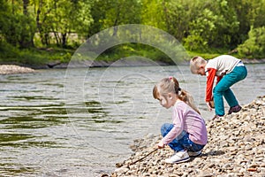 Children boy and girl playing near the river