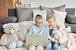 Children boy and girl playing on tabletand watching videos on laptop. Home schooler kids with dog, home schooling, home education