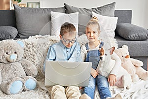 Children boy and girl playing on tabletand watching videos on laptop. Home schooler kids with dog, home schooling, home education