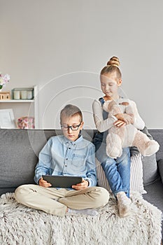 Children boy and girl playing on tabletand watching videos on laptop. Home schooler kids, home schooling, home education concept.