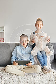 Children boy and girl playing on tabletand watching videos on laptop. Home schooler kids, home schooling, home education concept.