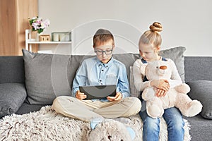 Children boy and girl playing on tabletand watching videos on laptop. Home schooler kids, home schooling, home education concept.