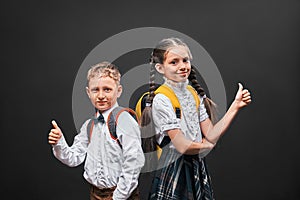 Children boy and girl students communicate at school. the girl stands with her back to the boy and both show a gesture of approval