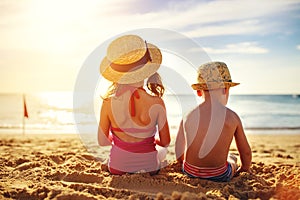 Children boy and girl in swimsuit sit on beach back