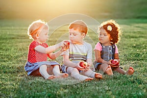 Children boy and girls sitting together sharing and eating apple food