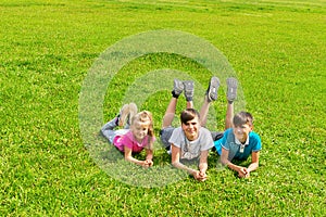 Children boys and girl lie on the grass on green meadow in the park. Summer concept, children`s games in the fresh air.