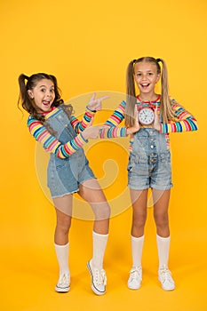 Children break concept. two cheerful girls hold alarm clock. back to school. summertime. discipline and time management