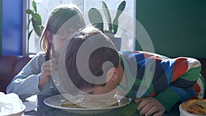 Children breakfast, joyful kids eating pancakes in canteen against window