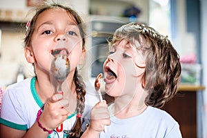 Children brother and sister eat chocolate from spoon