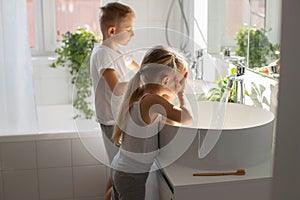 Children brother and sister wash and brush their teeth in the bathroom