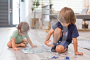 Children brothers boys at home during quarantine orders working on a puzzle activity together