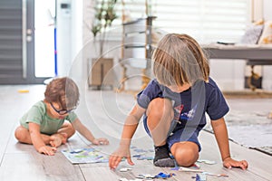 Children brothers boys at home during quarantine orders working on a puzzle activity together