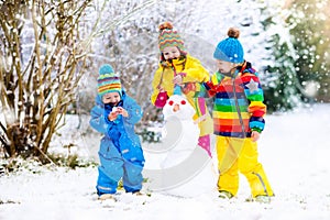 Kids building snowman. Children in snow. Winter fun.
