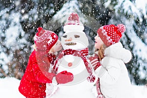 Kids building snowman. Children in snow. Winter fun.