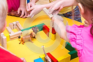 Children build a zoo of wooden bricks on table
