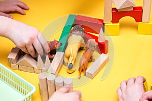 Children build a zoo of wooden bricks on table