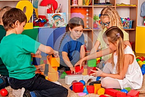 Children building blocks in kindergarten. Group kids playing toy floor .