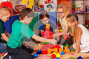 Children building blocks in kindergarten. Group kids playing toy floor.