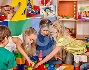 Children building blocks in kindergarten. Group kids playing toy floor .