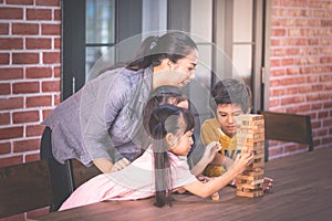 Children building toy block tower with teacher