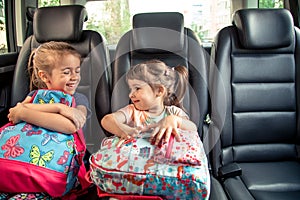 Children in the car go to school, happy, sweet faces of sisters