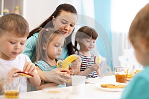 Children and carer together eat fruits in kindergarten or daycare