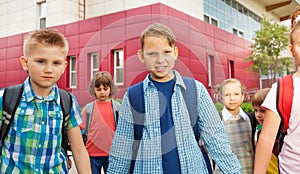 Children carry rucksacks and walk near school