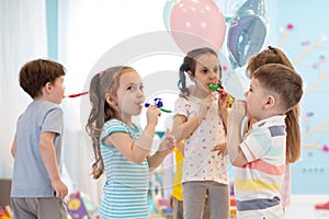 Children celebrating birthday party with noisemakers