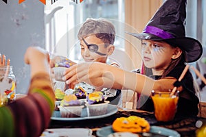 Children celebrating Halloween at kindergarten eating thematic sweets