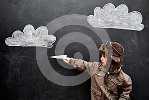 Children, chalkboard and paper plane with boy in studio on black background for fantasy game. Education, class and kid