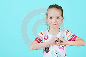 Children, Charity, Healthcare, Adoption Concept. Smiling little girl making heart-shape gesture.