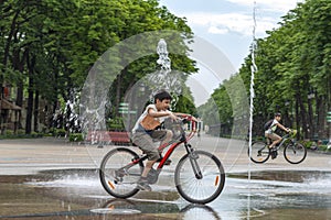 Children children have fun riding bicycles by the fountain on a hot summer day in a park