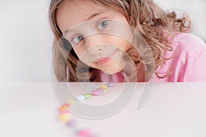 Children and chocolate. Joyful girl with sweets.A cheerful girl plays and eats chocolate multi-colored round candies on a light