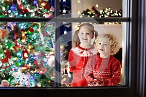 Children at Christmas tree. Kids at fireplace on Xmas eve