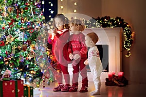 Children at Christmas tree. Kids at fireplace on Xmas eve