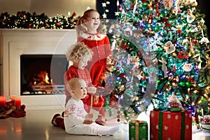 Children at Christmas tree. Kids at fireplace on Xmas eve