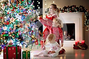 Children at Christmas tree. Kids at fireplace on Xmas eve