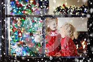 Children at Christmas tree. Kids at fireplace on Xmas eve