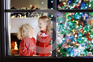 Children at Christmas tree. Kids at fireplace on Xmas eve