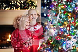 Children at Christmas tree. Kids at fireplace on Xmas eve