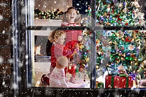 Children at Christmas tree. Kids at fireplace on Xmas eve