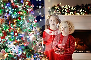 Children at Christmas tree. Kids at fireplace on Xmas eve