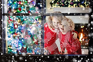 Children at Christmas tree. Kids at fireplace on Xmas eve