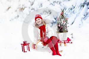 Children with Christmas tree. Snow winter fun for kids.