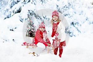 Children with Christmas tree. Snow winter fun for kids.