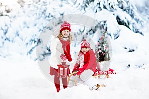 Children with Christmas tree. Snow winter fun for kids.