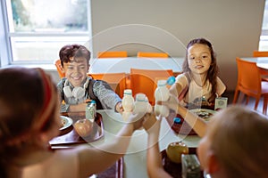 Children clanging their bottles of juice while having lunch