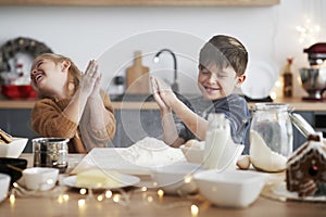 Children clasping using flour while baking cookies for Christmas