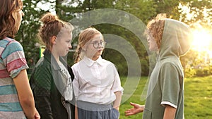 Children classmates talk to each other during a walk in the park, school friendship, back to school. Sunset, lins flare